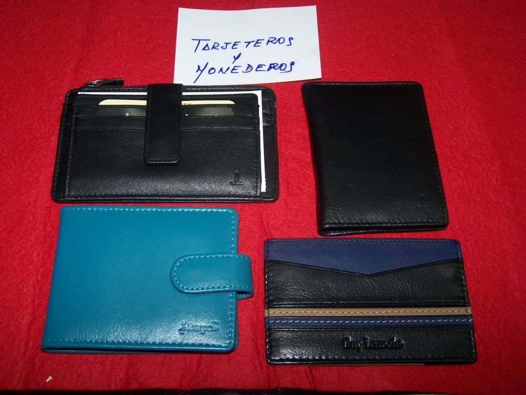 Cuatro carteras están alineadas sobre una mesa roja con una nota que dice 