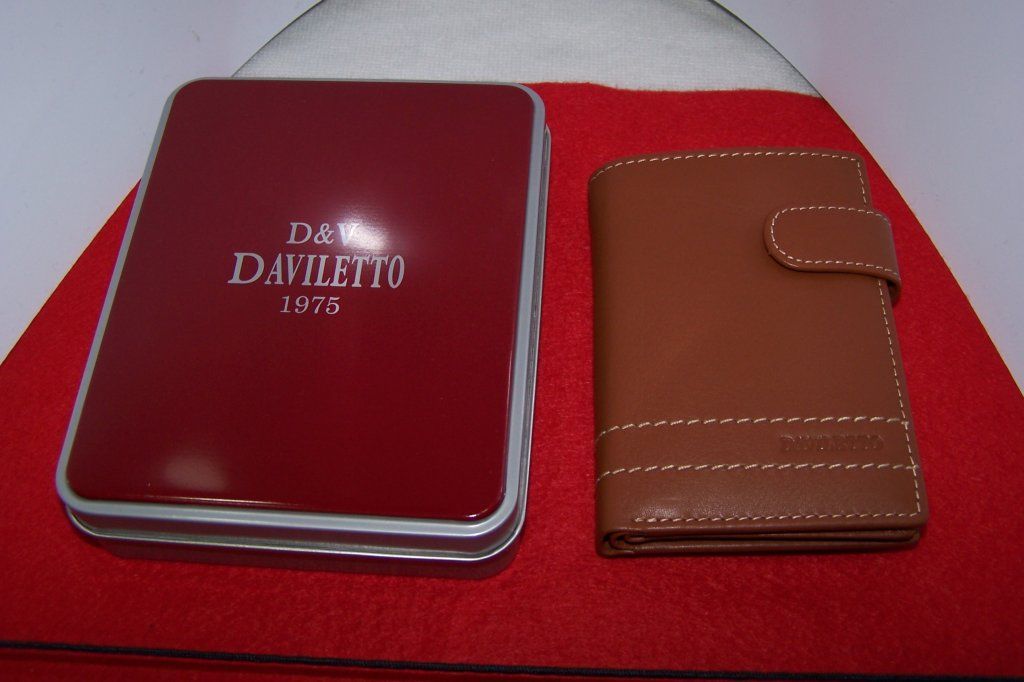 Una billetera marrón junto a un cuadro rojo que dice daviletto 1876
