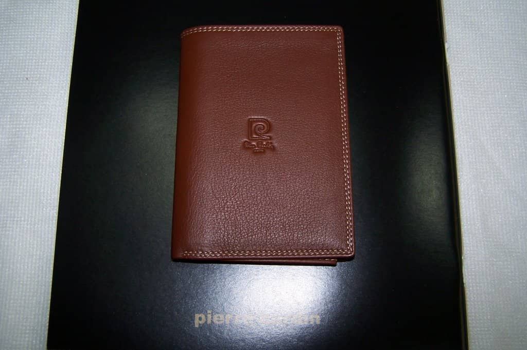 Una billetera de cuero marrón está encima de un libro negro.