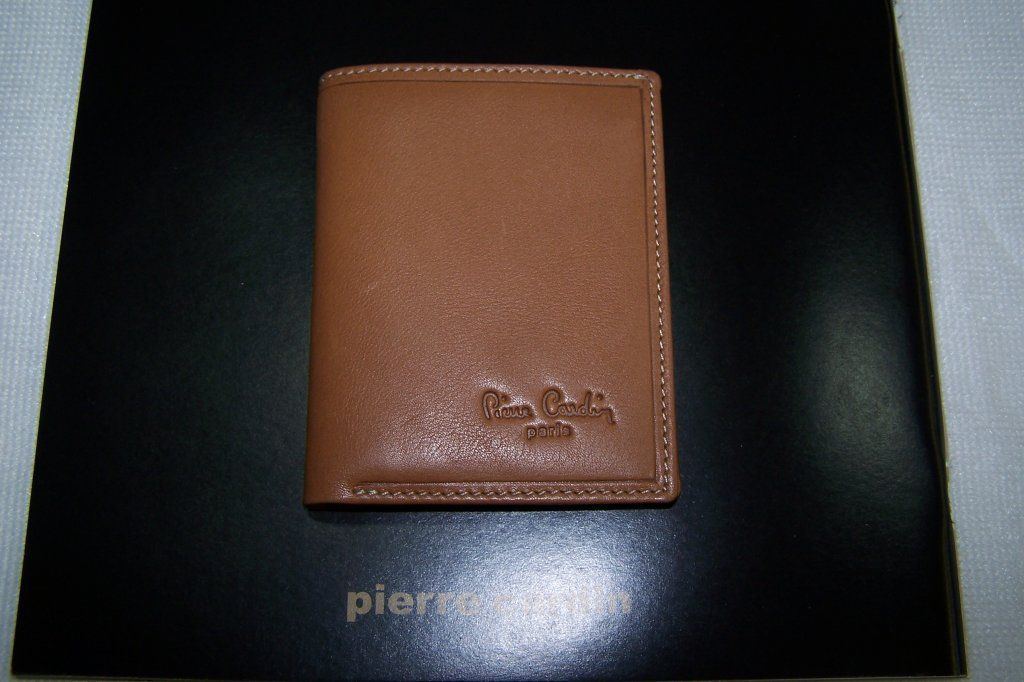 Una billetera marrón de Pierre Cardin reposa sobre una superficie negra.