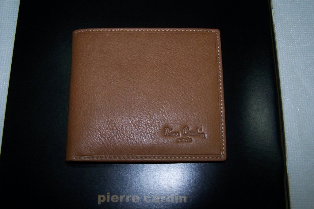 Una billetera marrón de Pierre Cardin está encima de una caja negra.