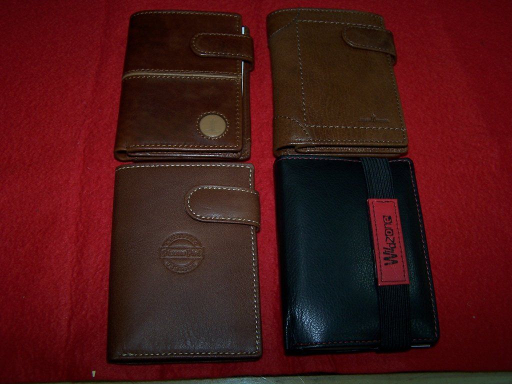 Una billetera marrón y una billetera negra están sobre una tela roja.