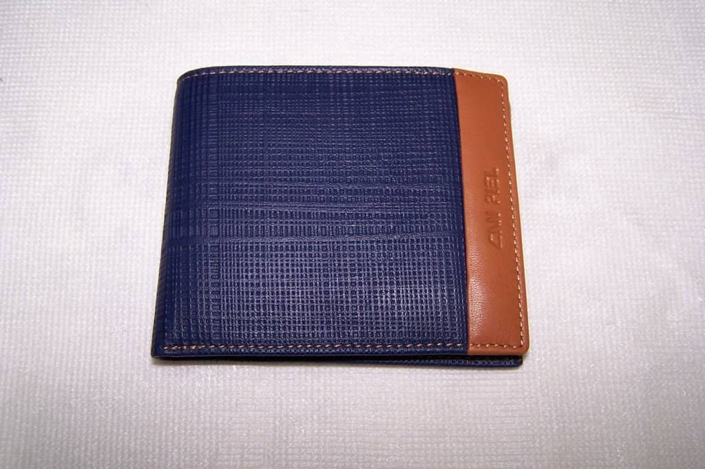 Una billetera azul y marrón está sobre una superficie blanca.