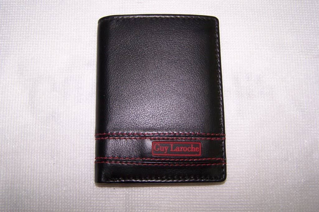 Un hombre negro con una billetera Laroche está sentado sobre una superficie blanca.