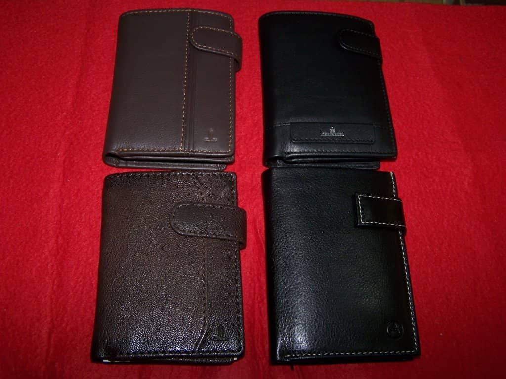 Cuatro carteras negras están alineadas sobre una tela roja.