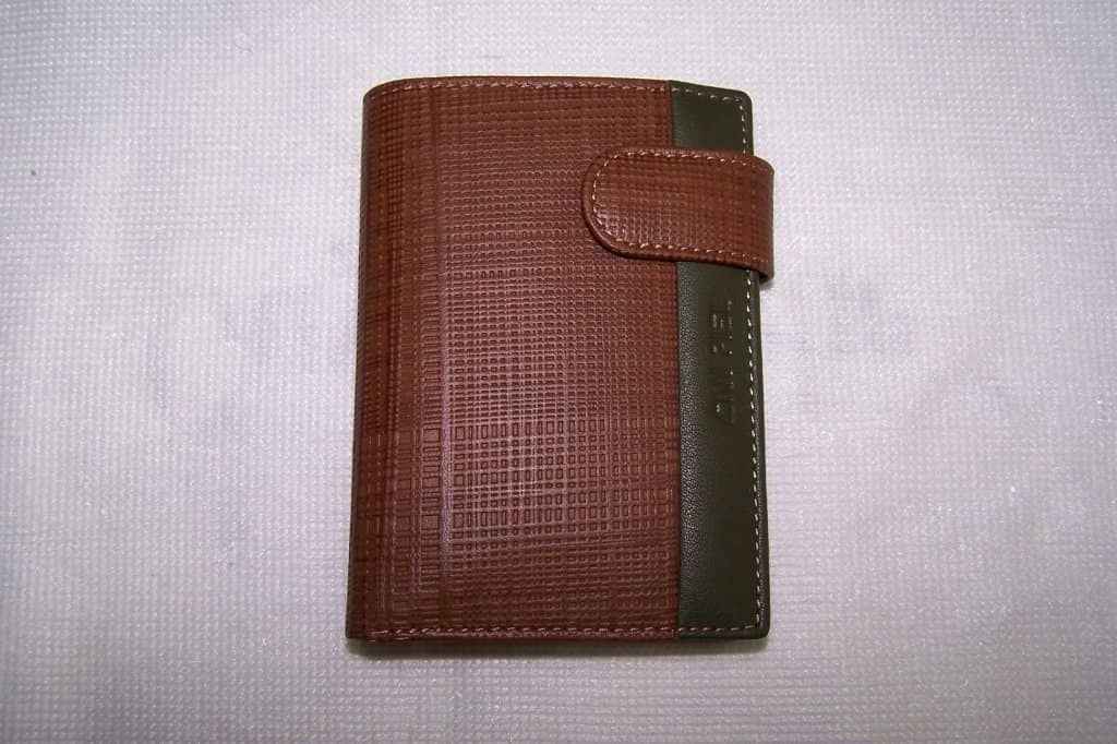 Una billetera marrón reposa sobre una superficie blanca.