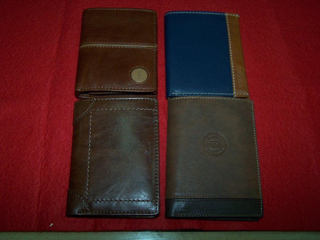 Cuatro carteras de cuero están alineadas sobre una tela roja.