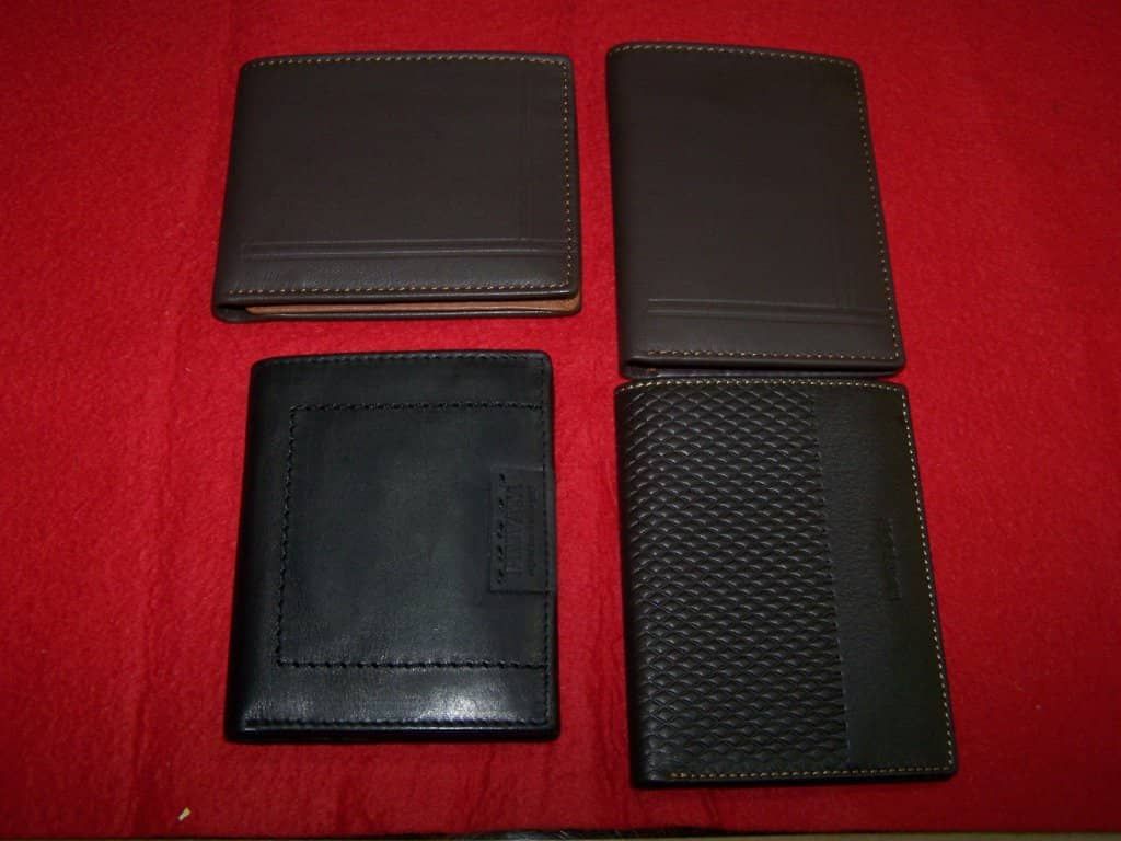 Cuatro carteras negras están alineadas sobre una tela roja.