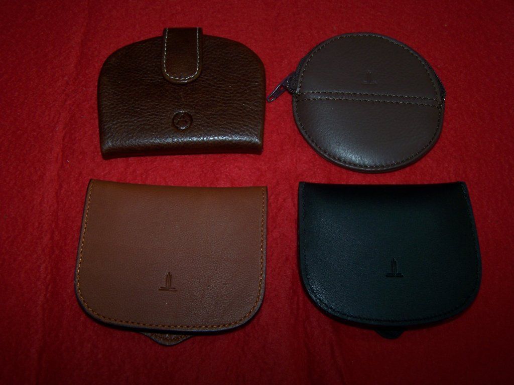 Cuatro carteras de cuero están alineadas sobre una superficie roja.