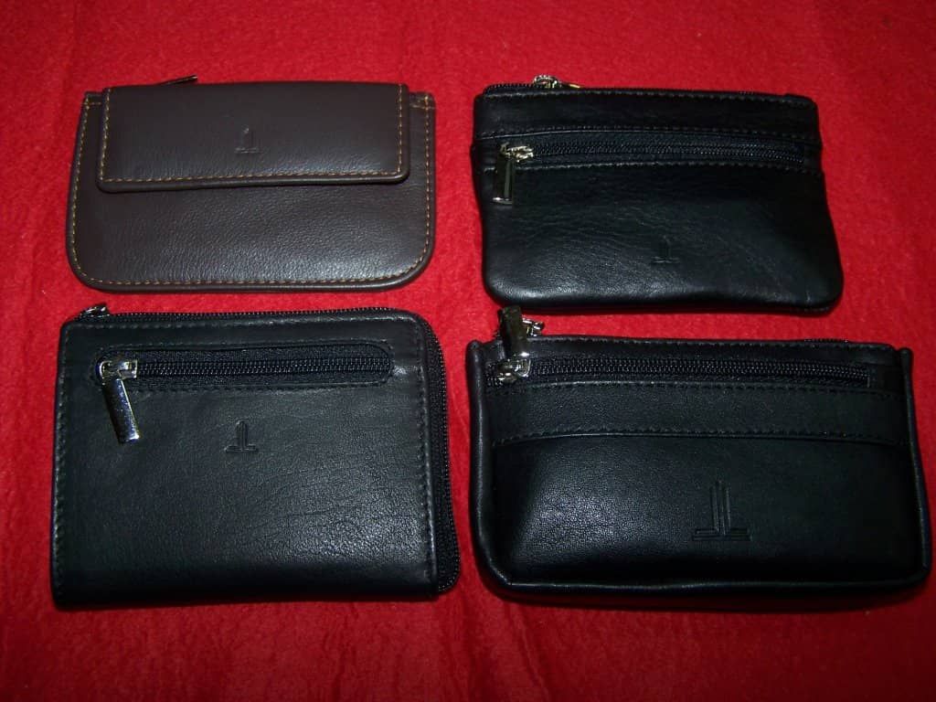 Cuatro carteras de cuero negro están alineadas sobre una superficie roja