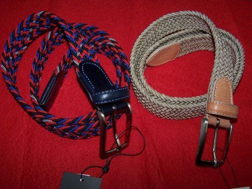 Dos cinturones trenzados están sobre una superficie roja.