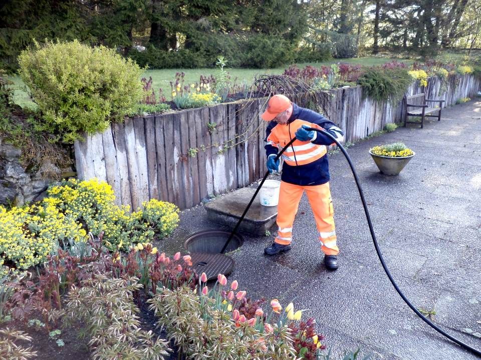Mitarbeiter führt Werkzeug in Kanal ein, Garten, OBAG Kanalreinigung