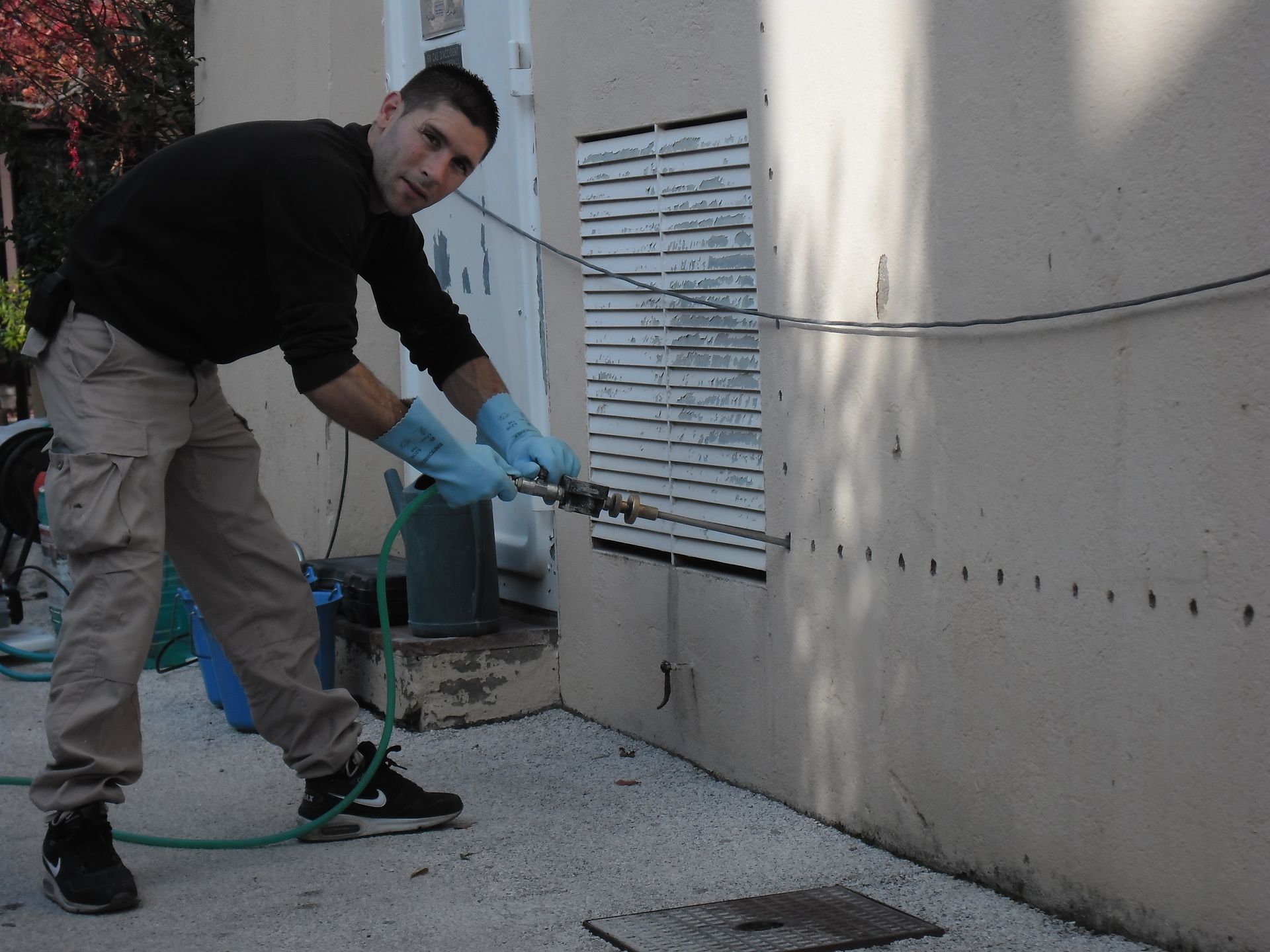 Un homme utilisant une perceuse électrique pour forer un trou dans un mur en béton.