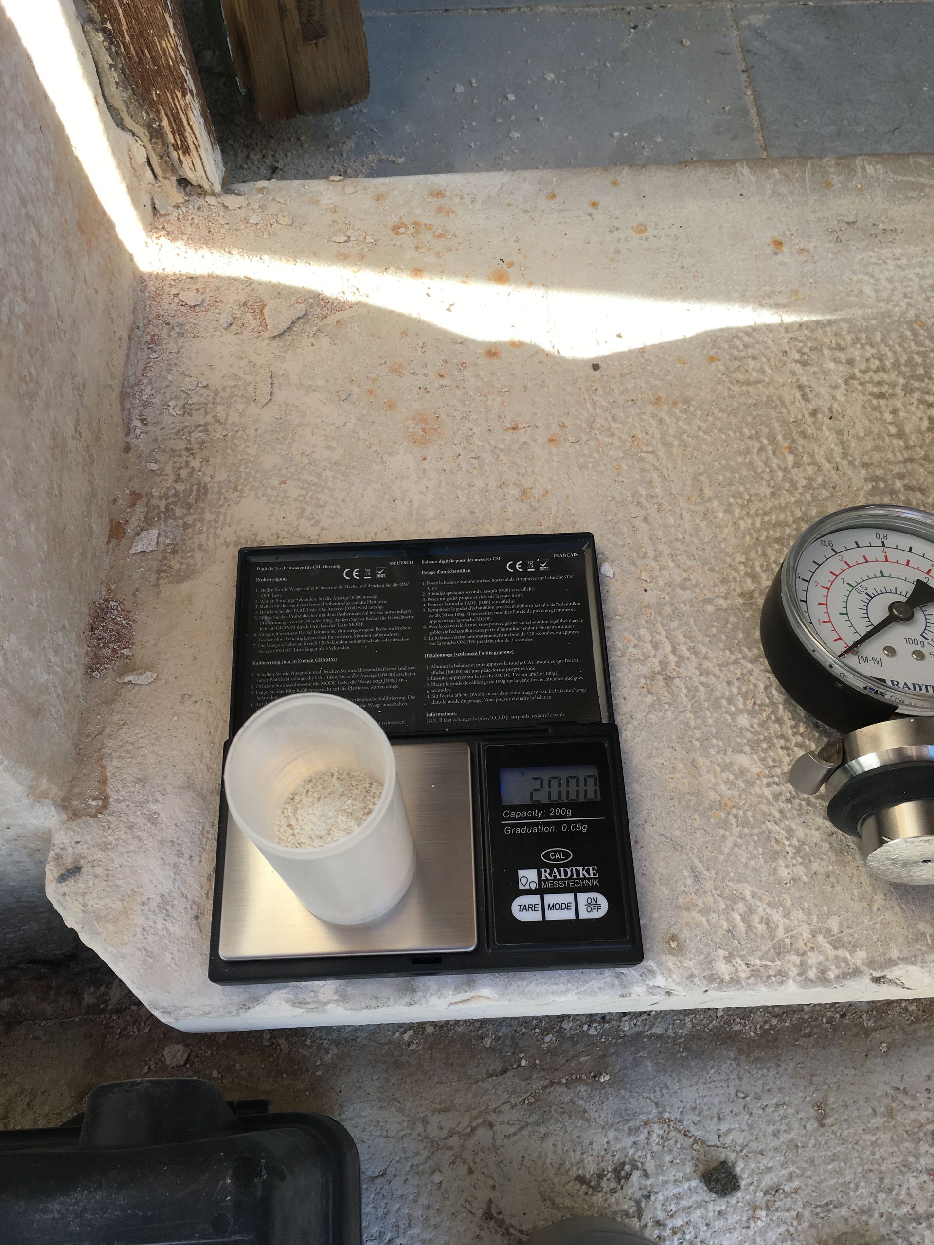 Une balance électronique affichant le poids d'un récipient contenant des échantillons de matériaux