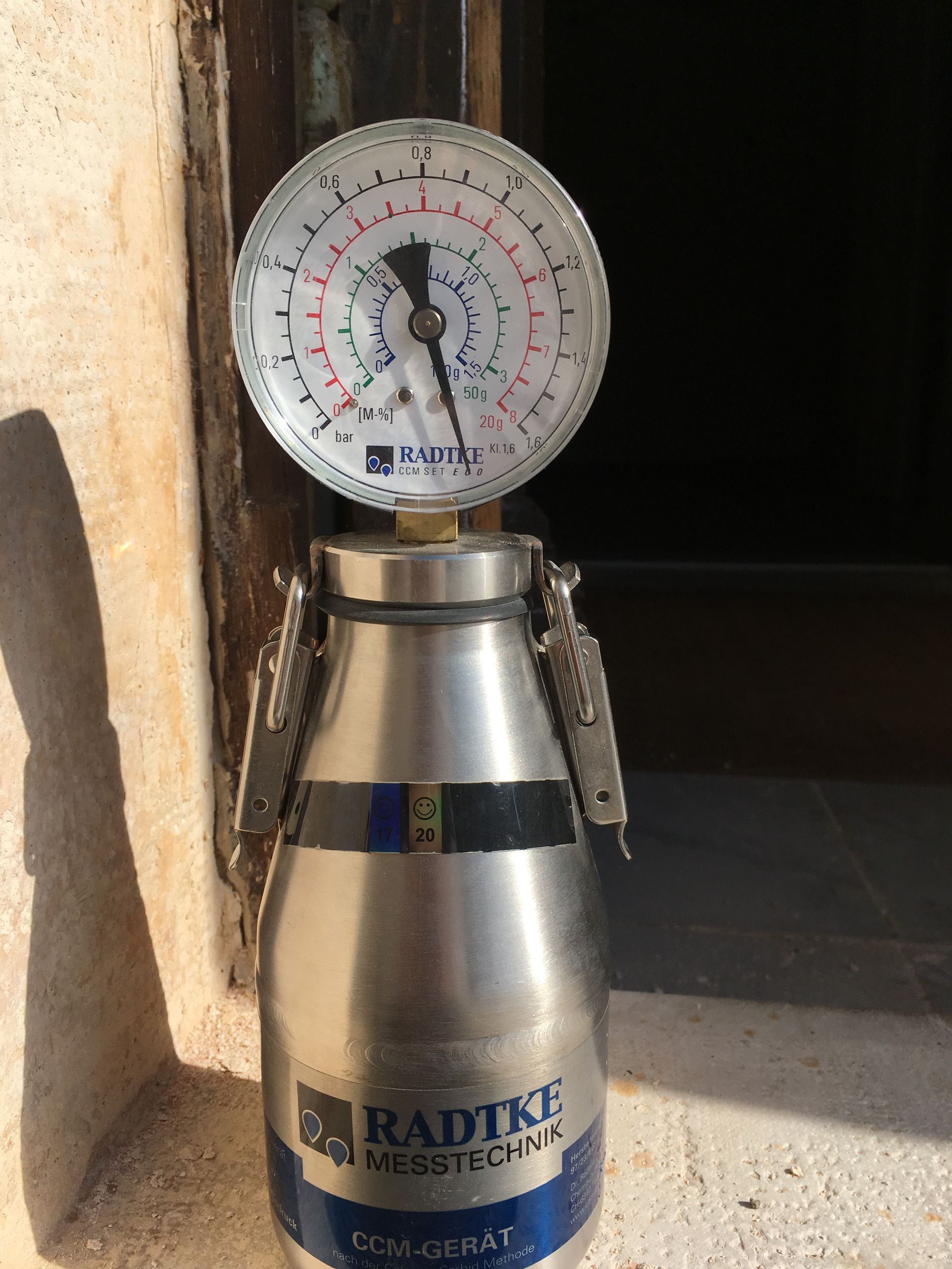 Un manomètre analogique connecté à un cylindre métallique, utilisé pour des mesures de pression.