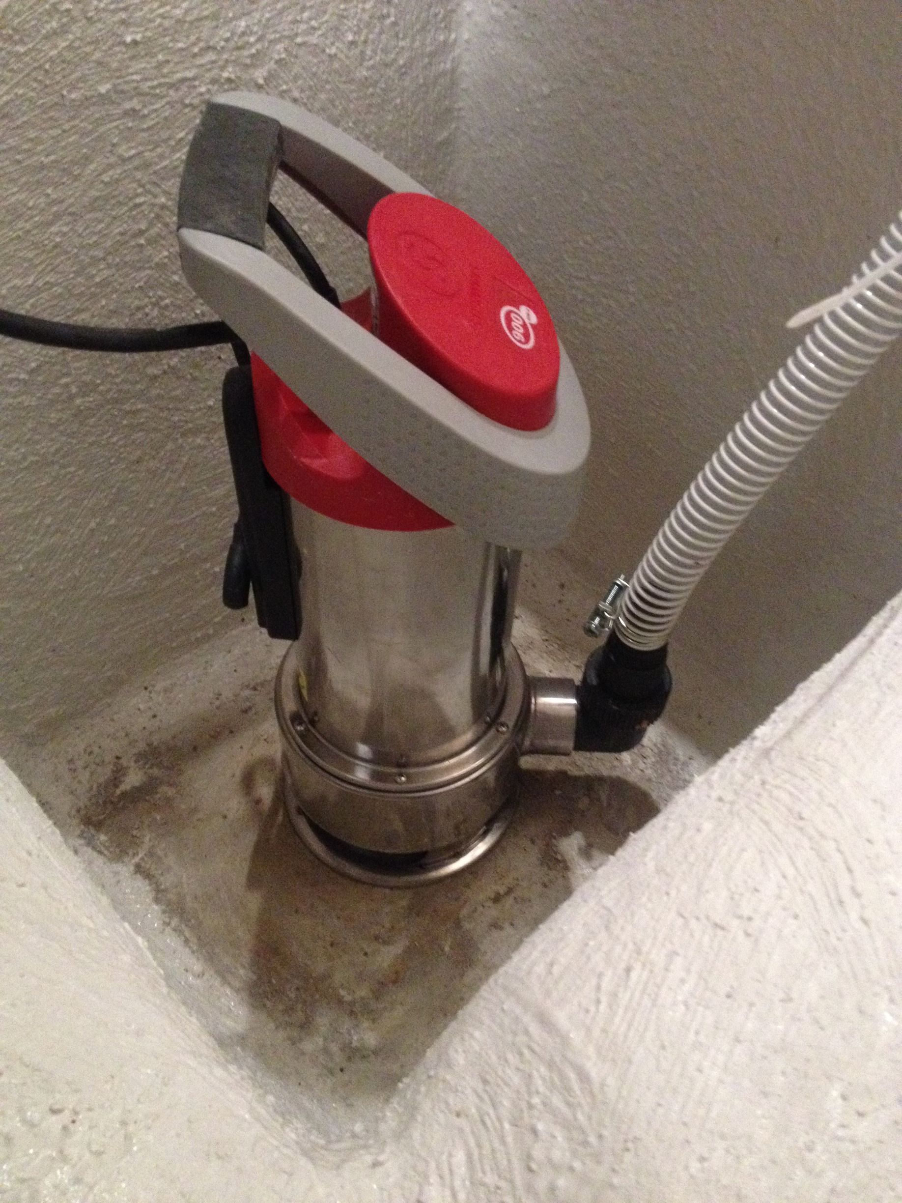 Un gros plan du dispositif électronique rouge et blanc fixé sur un tuyau en plastique blanc. Le dispositif semble être un capteur ou un détecteur.