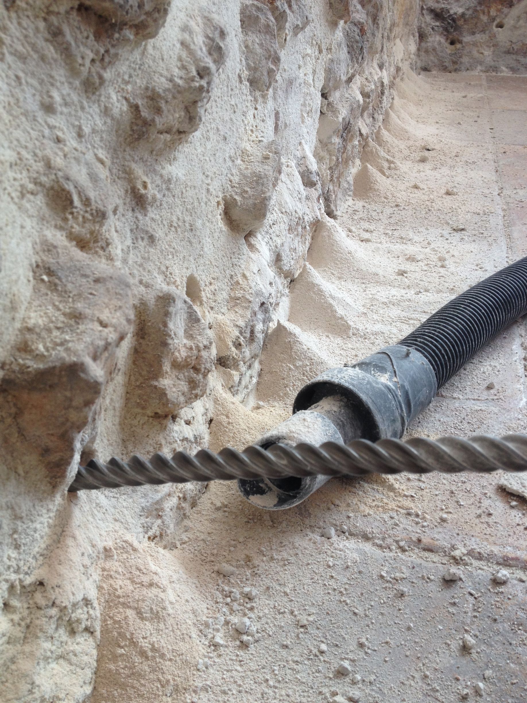 Foret perçant un trou dans un mur en béton avec un aspirateur pour la poussière.