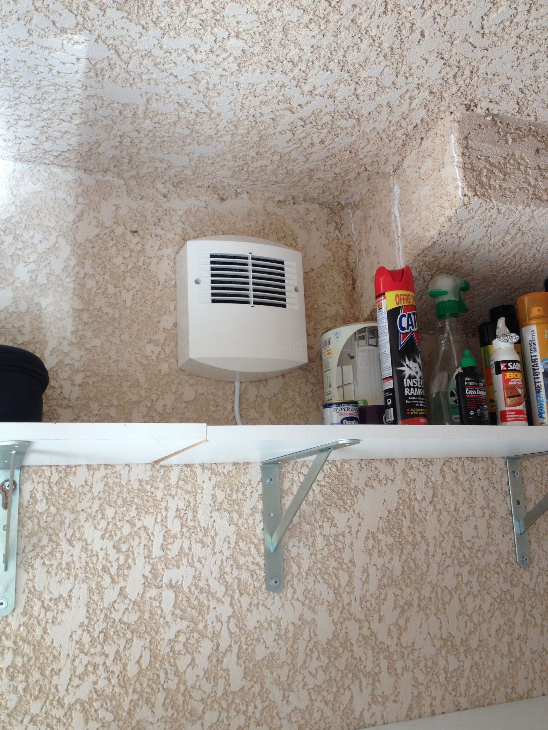 Ventilation fixé au mur au-dessus d'une étagère contenant des produits d'entretien