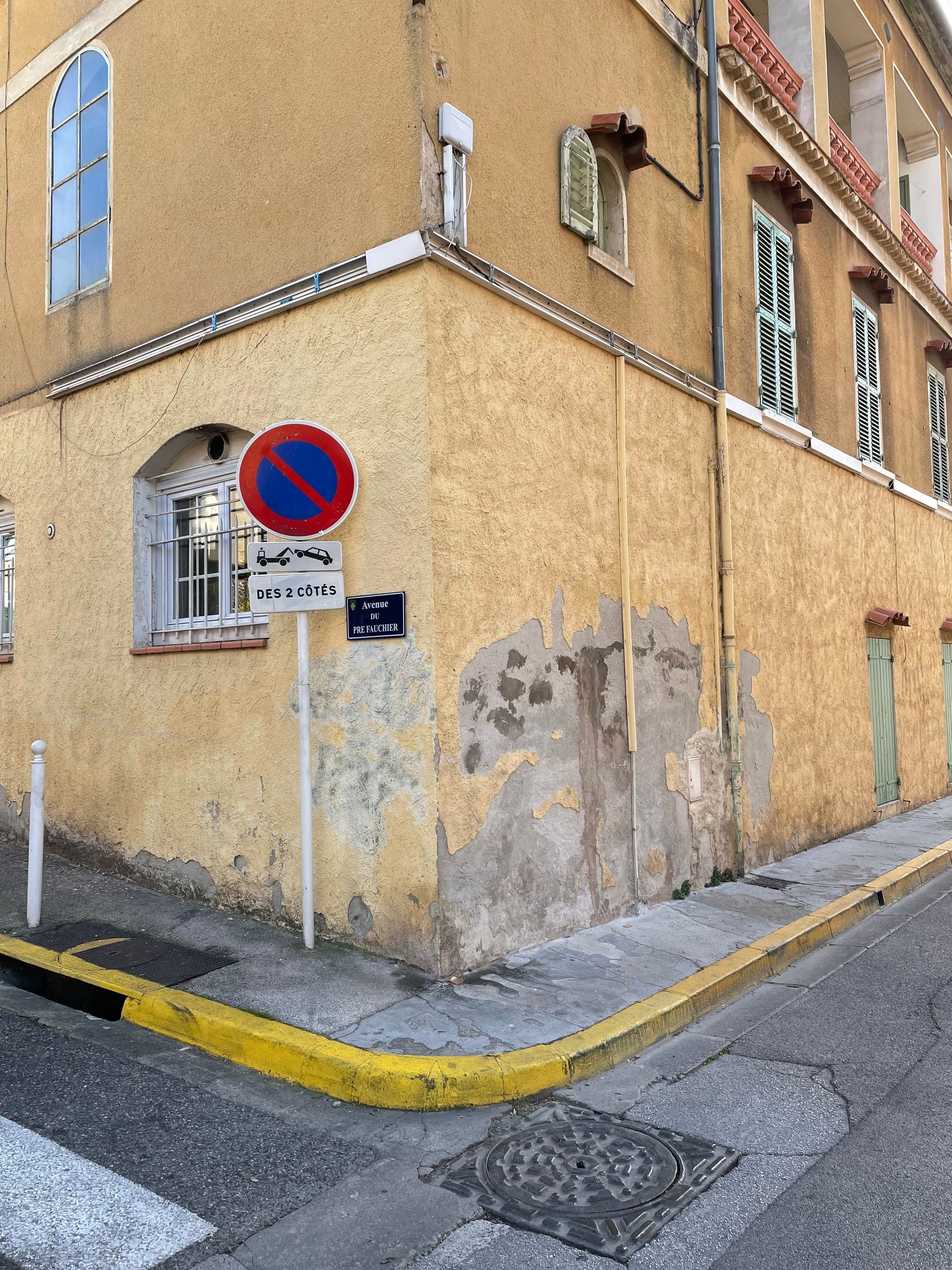 Mur extérieur endommagé avec des zones de plâtre manquant et des taches, montrant des signes de détérioration.