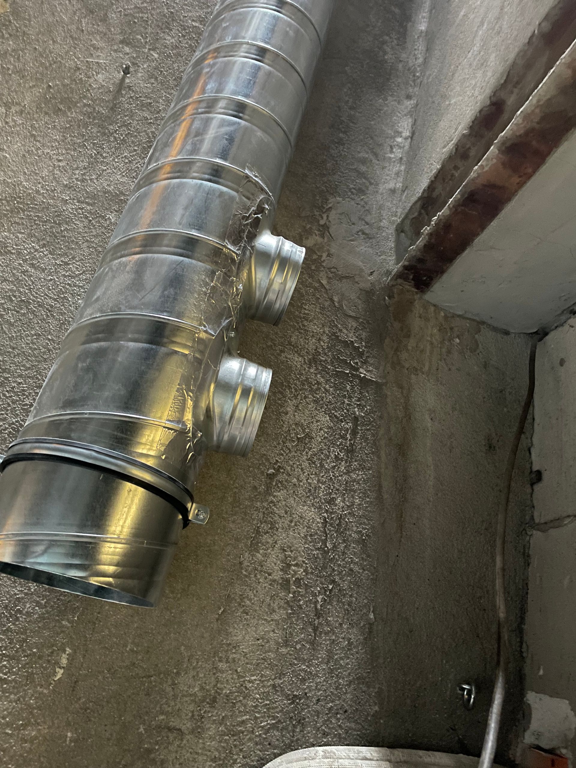 Plafond avec tuyaux et conduits enveloppés dans une isolation argentée.