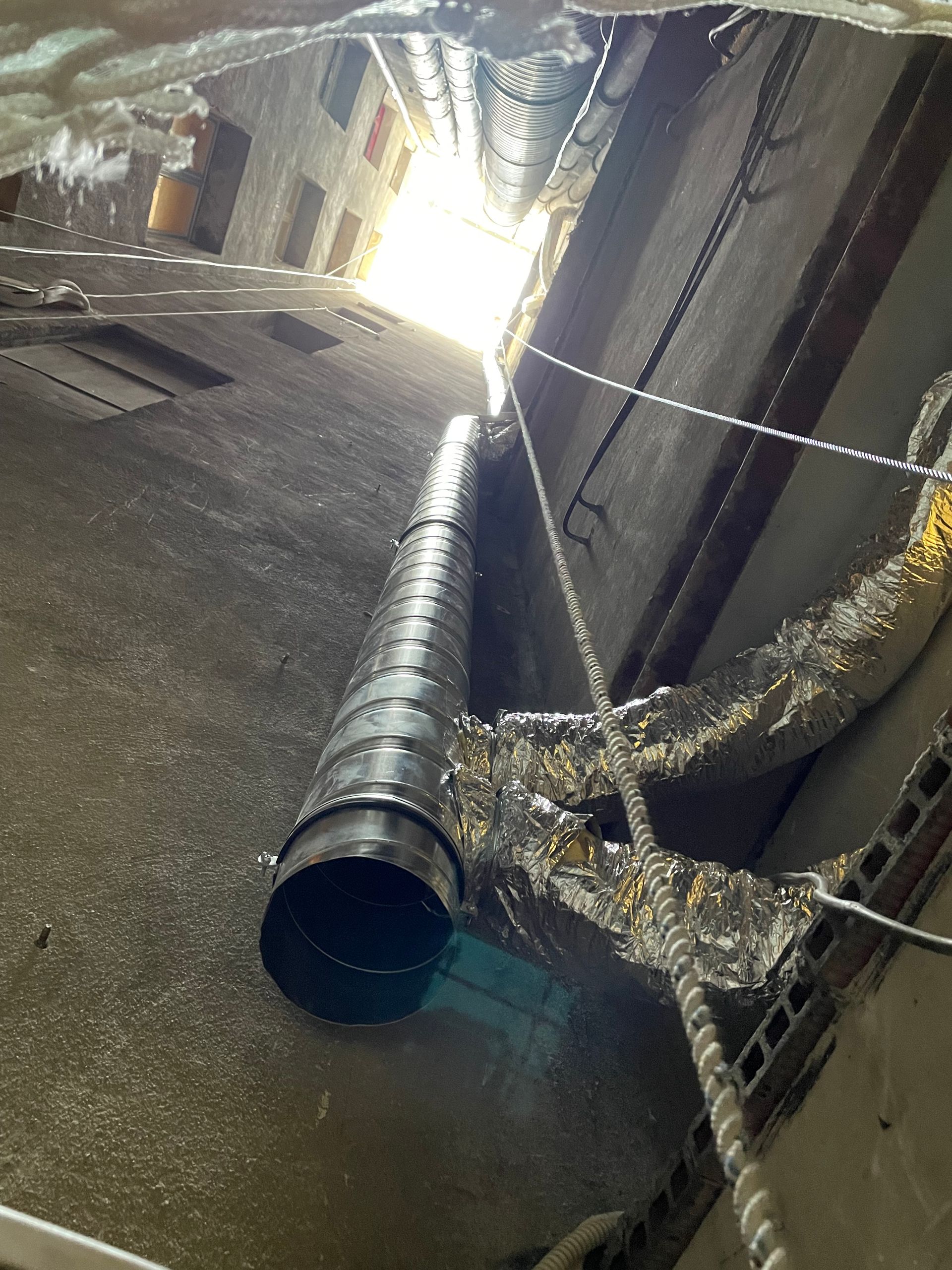 Mur intérieur gris détérioré avec tuyaux et conduits.