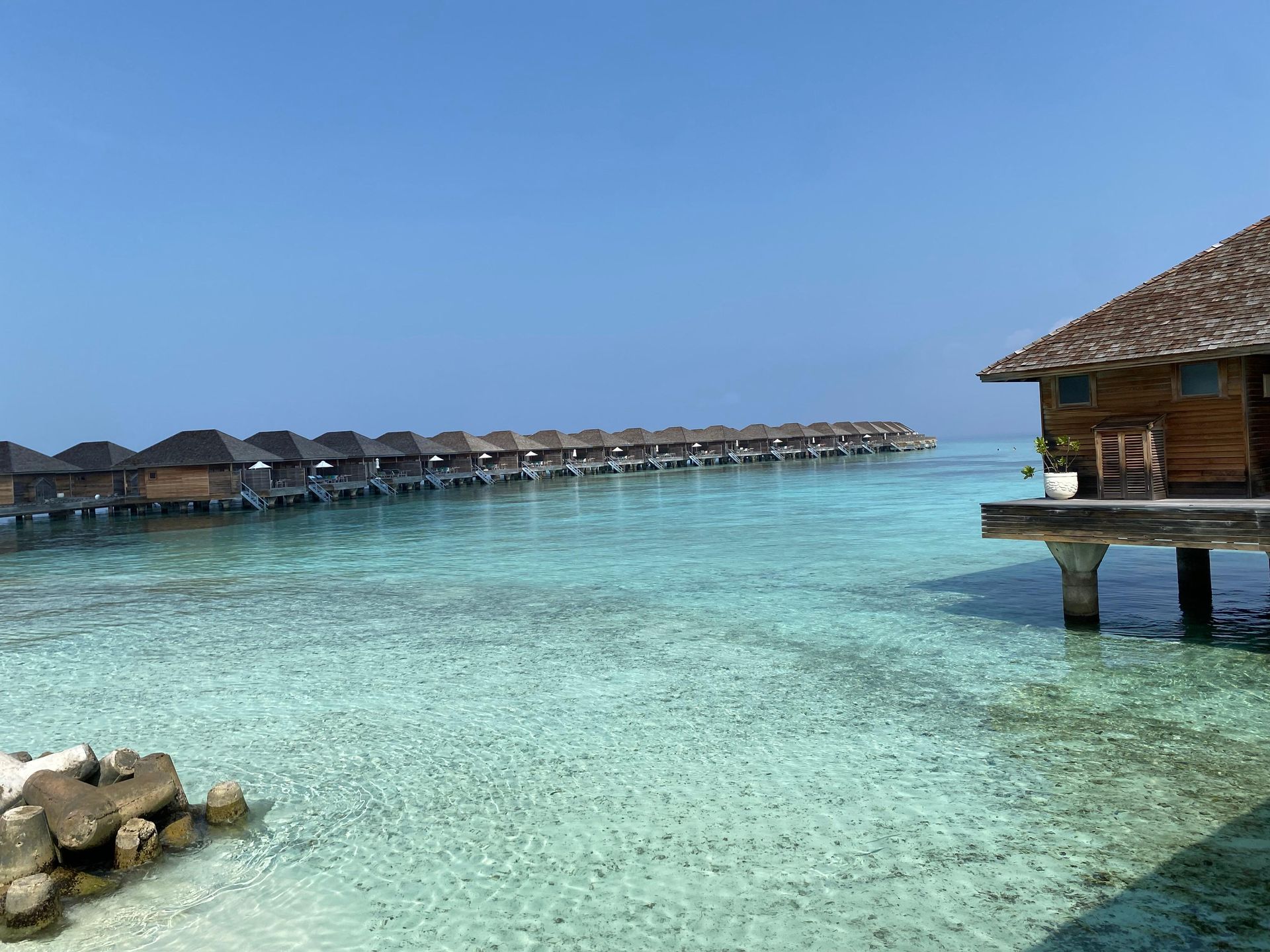 Bungalows über dem Wasser in einer türkisfarbenen Lagune unter klarem, blauem Himmel
