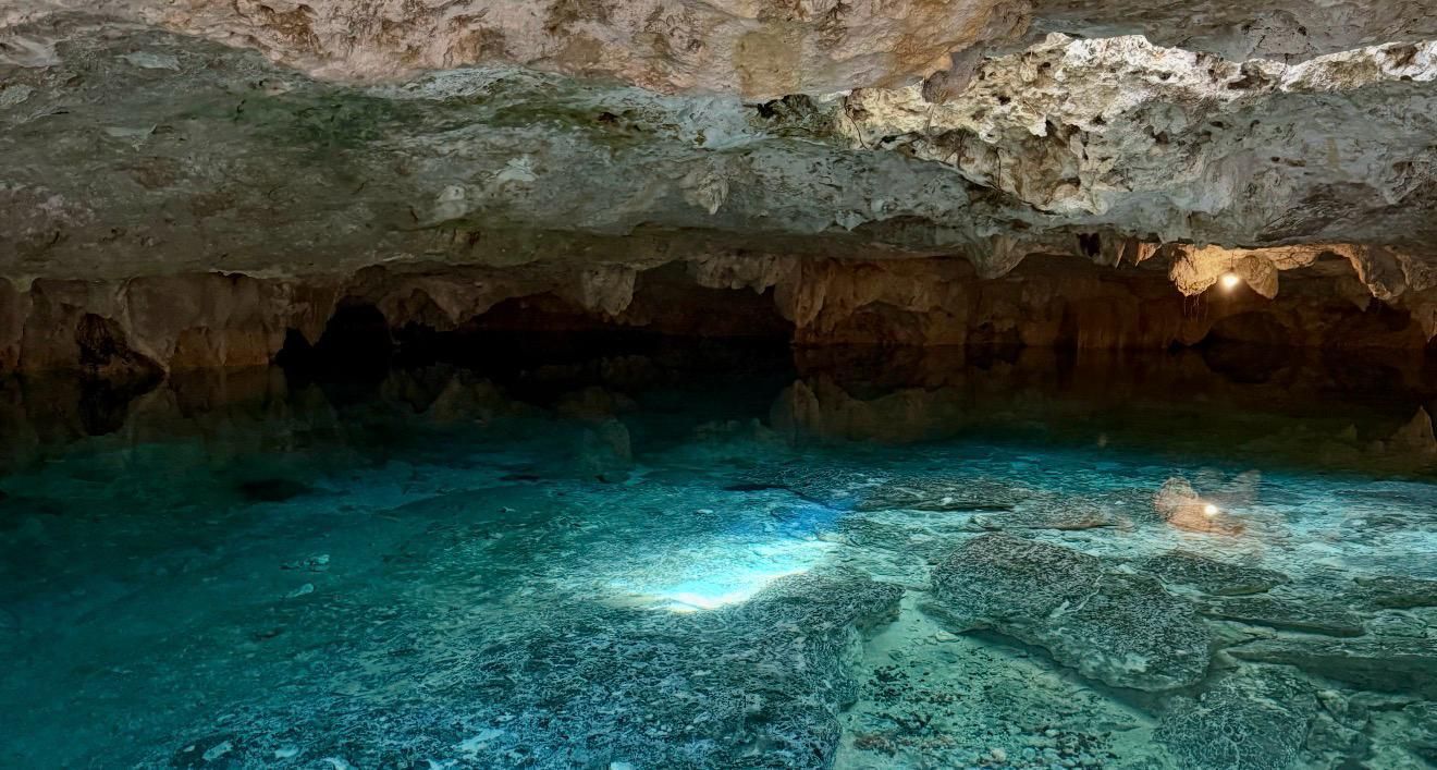 Kristallklares, türkisfarbenes Wasser in einer Felsenhöhle mit niedriger Steindecke