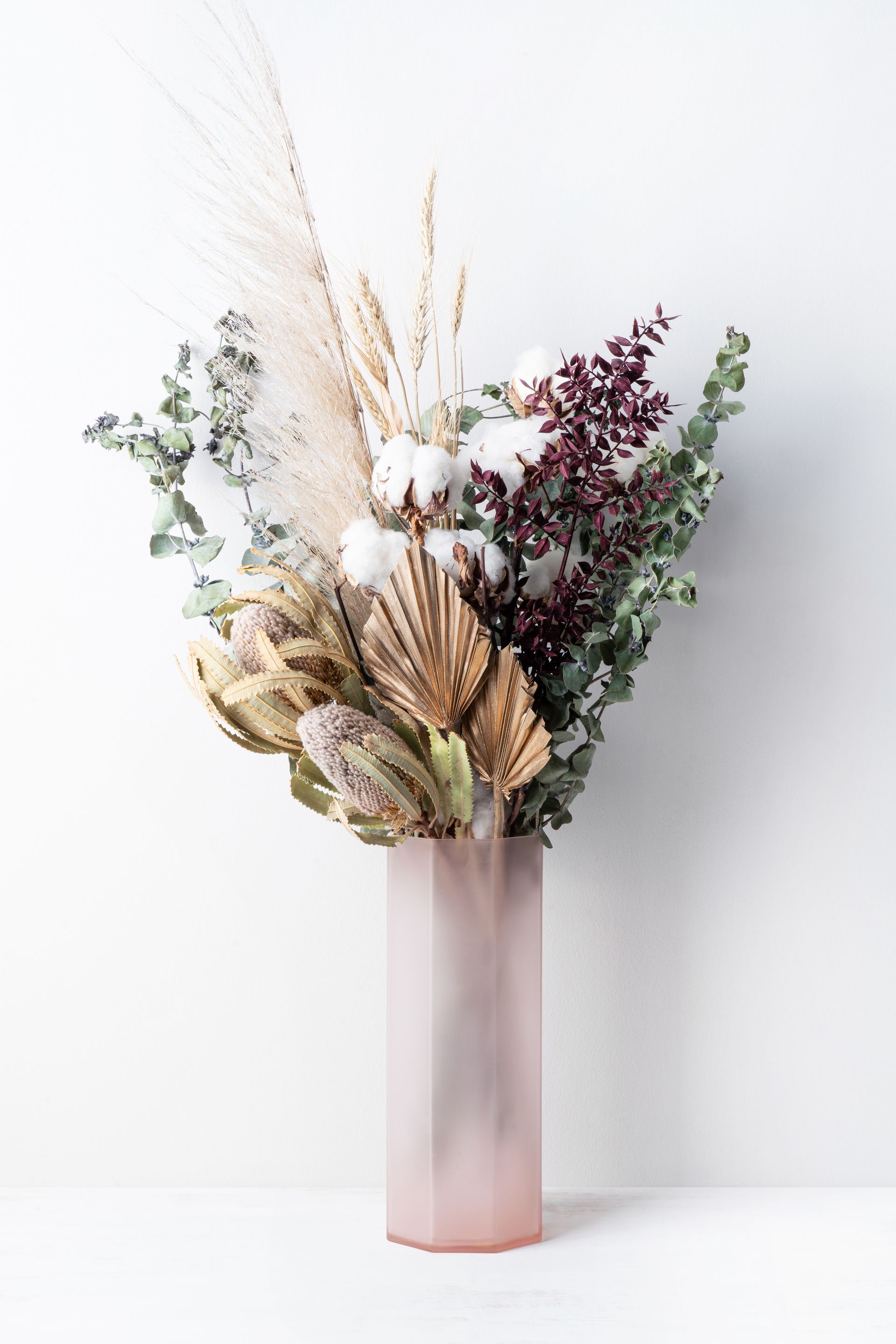 Un bouquet de fleurs séchées dans un vase rose