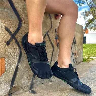 Una persona está sentada en una pared llevando un par de zapatos negros descalzos.