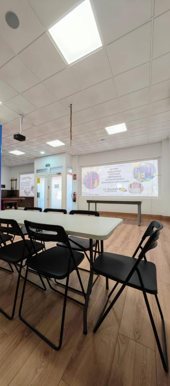 Una sala de conferencias con una mesa larga, sillas negras y una pizarra en la pared.