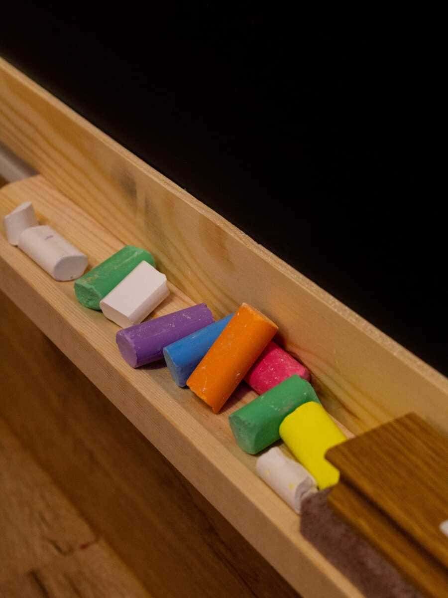 Lápiz de colores de madera, dispuestos en fila sobre una bandeja o estante de madera.