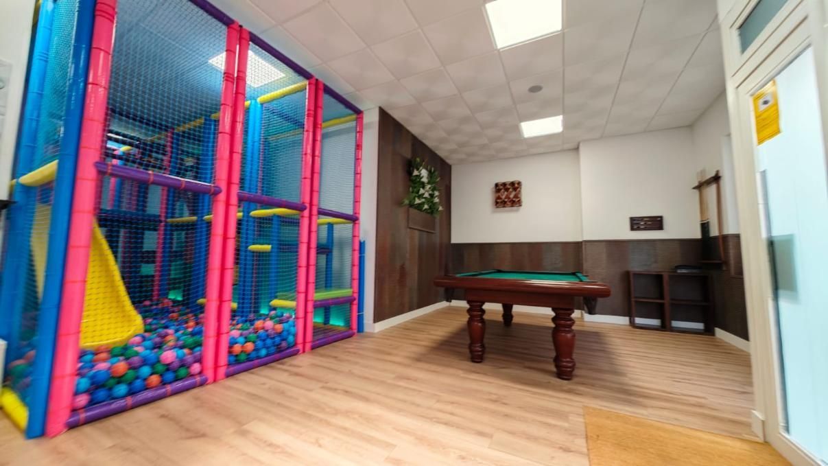 Zona de juegos interior con piscina de pelotas y mesa de billar.