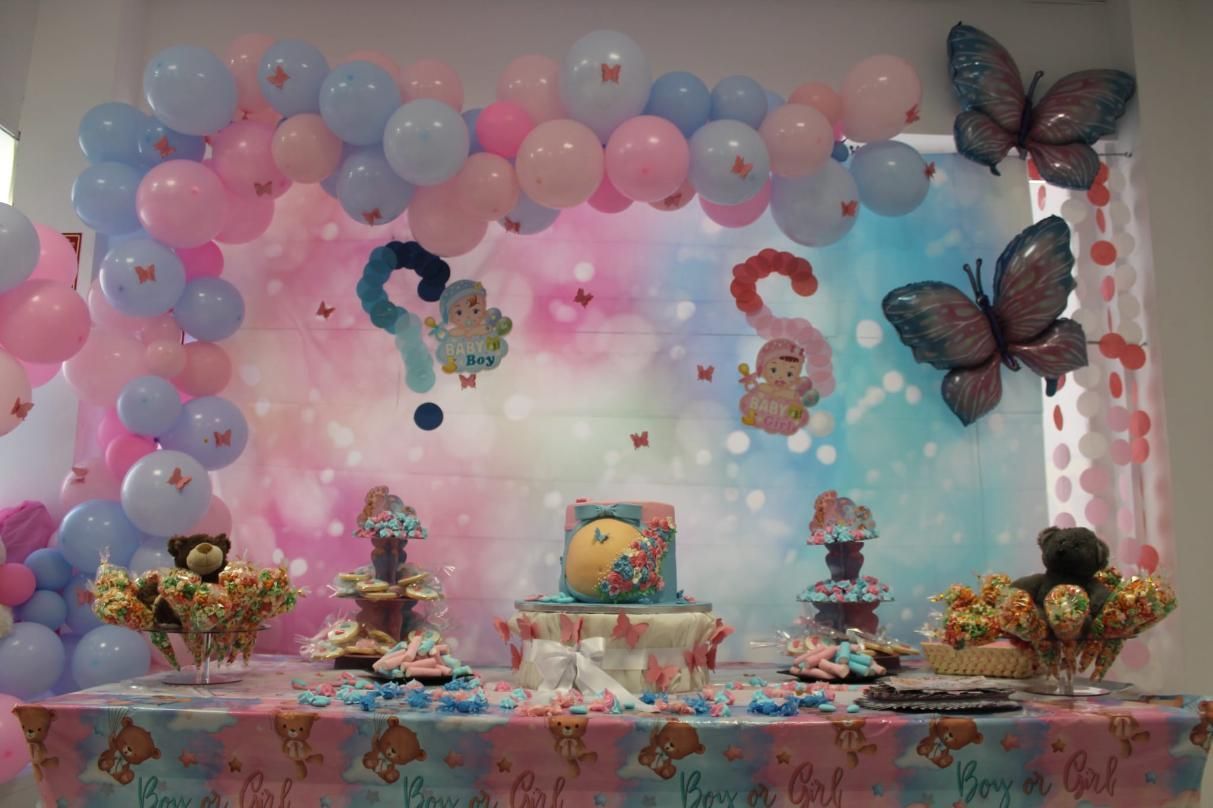 Fiesta de revelación de género con temática de mariposas, pastel, globos y golosinas en colores rosa, azul y pastel.