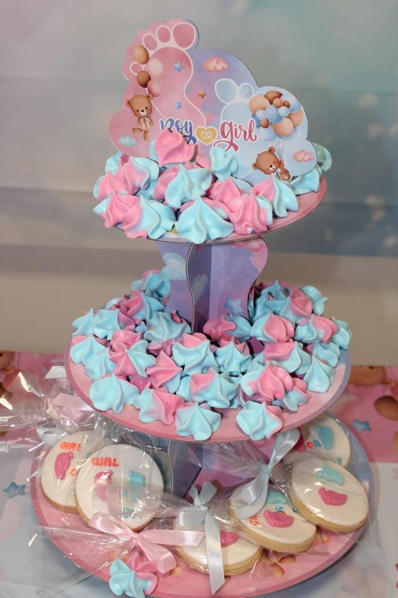 Pastel de baby shower de tres niveles con merengues rosas y azules, galletas y adorno 