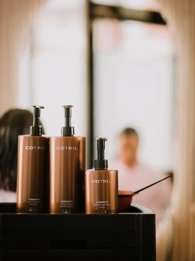 Tres botellas de producto para cabello castaño con bombas negras.