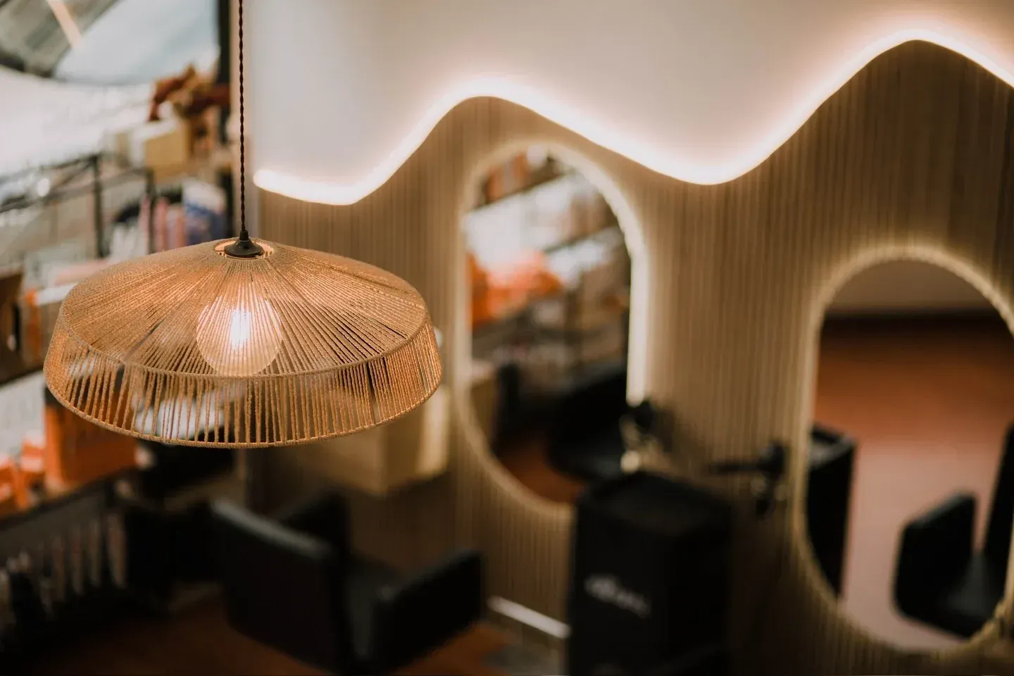 Lámpara con pantalla de cuerda en la peluquería. Espejos y molduras onduladas en las paredes. Sillas e iluminación interior.