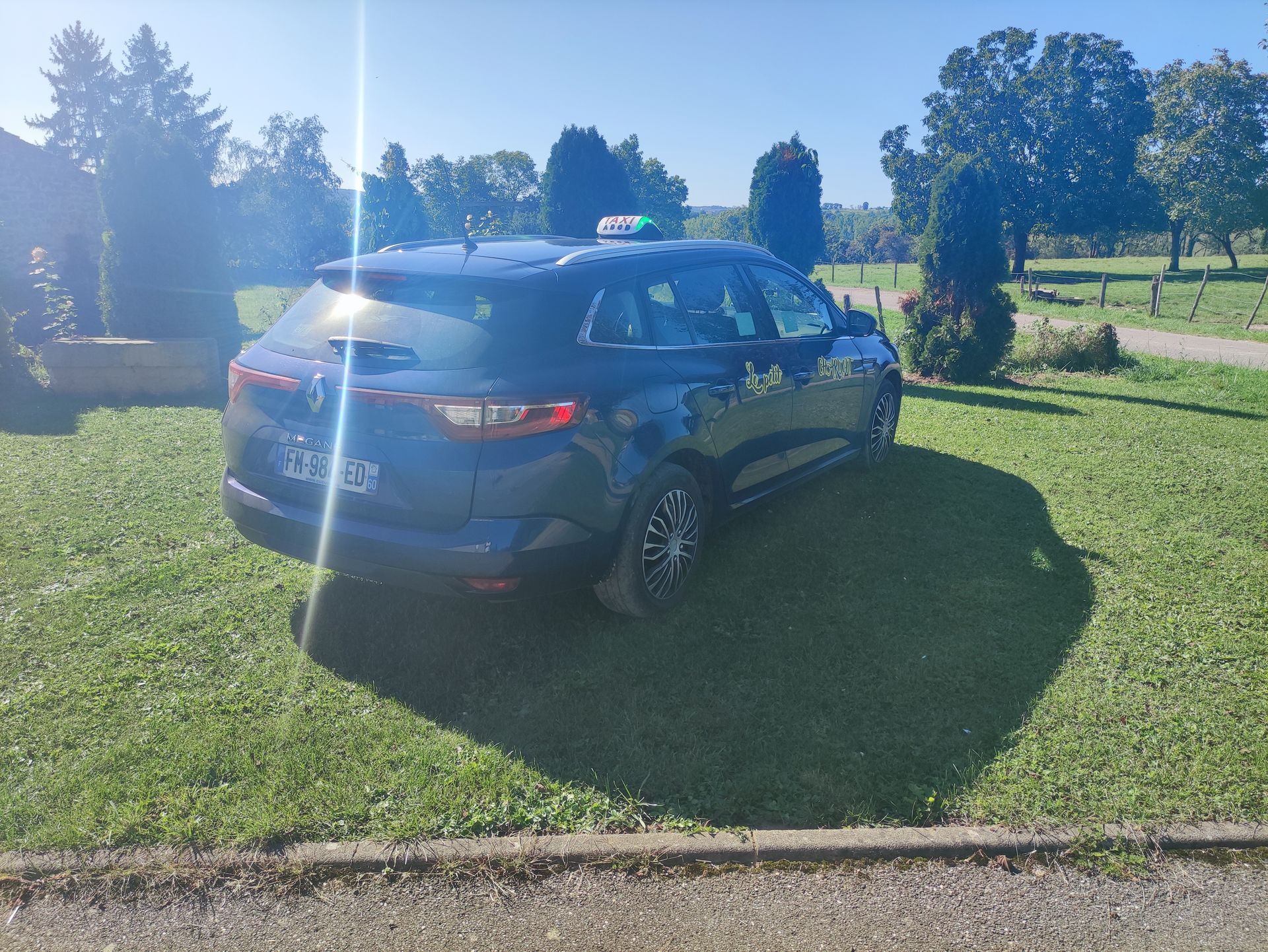 Une voiture blanche vue de profil garée près d'une maison de campagne