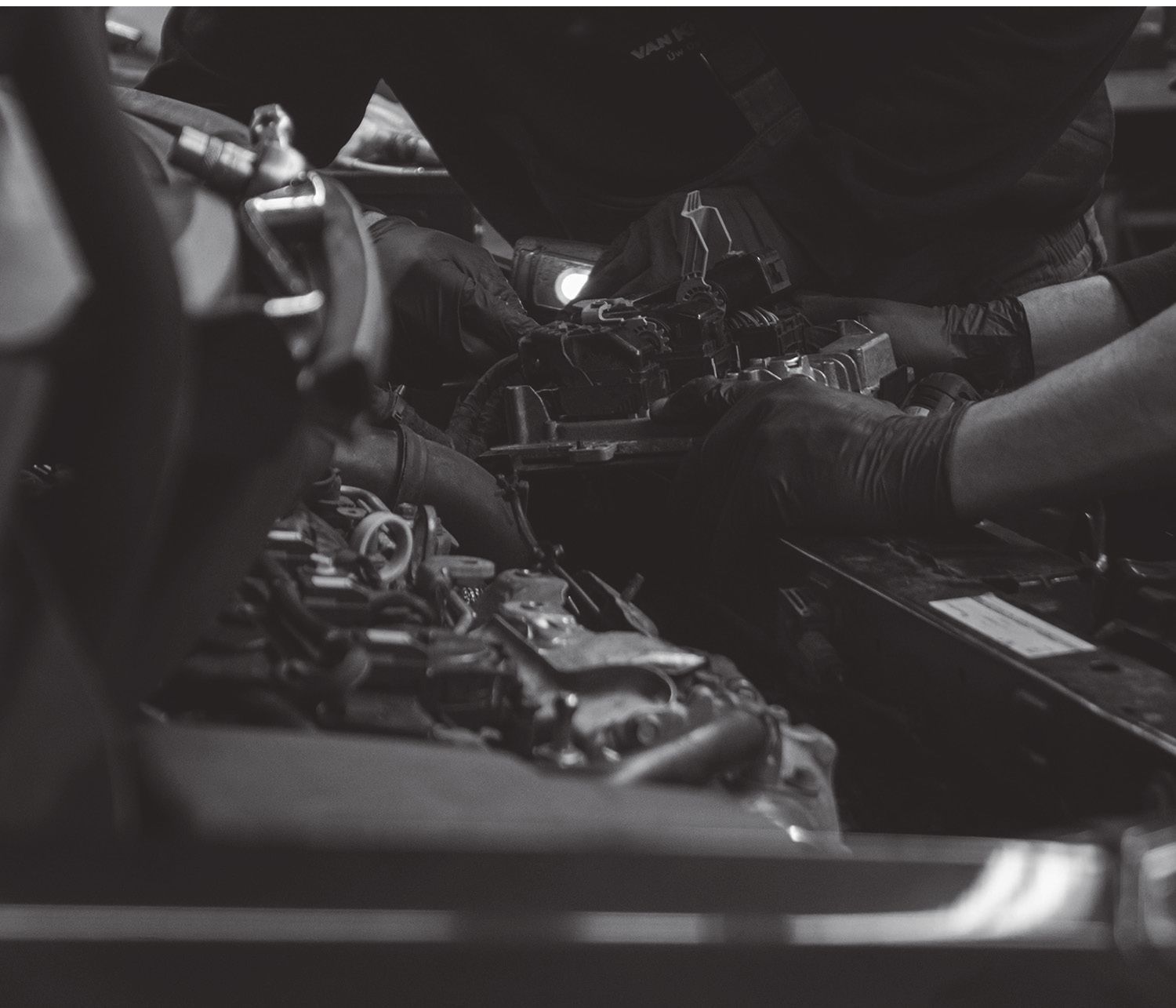 Una fotografía en blanco y negro de un hombre trabajando en el motor de un automóvil.