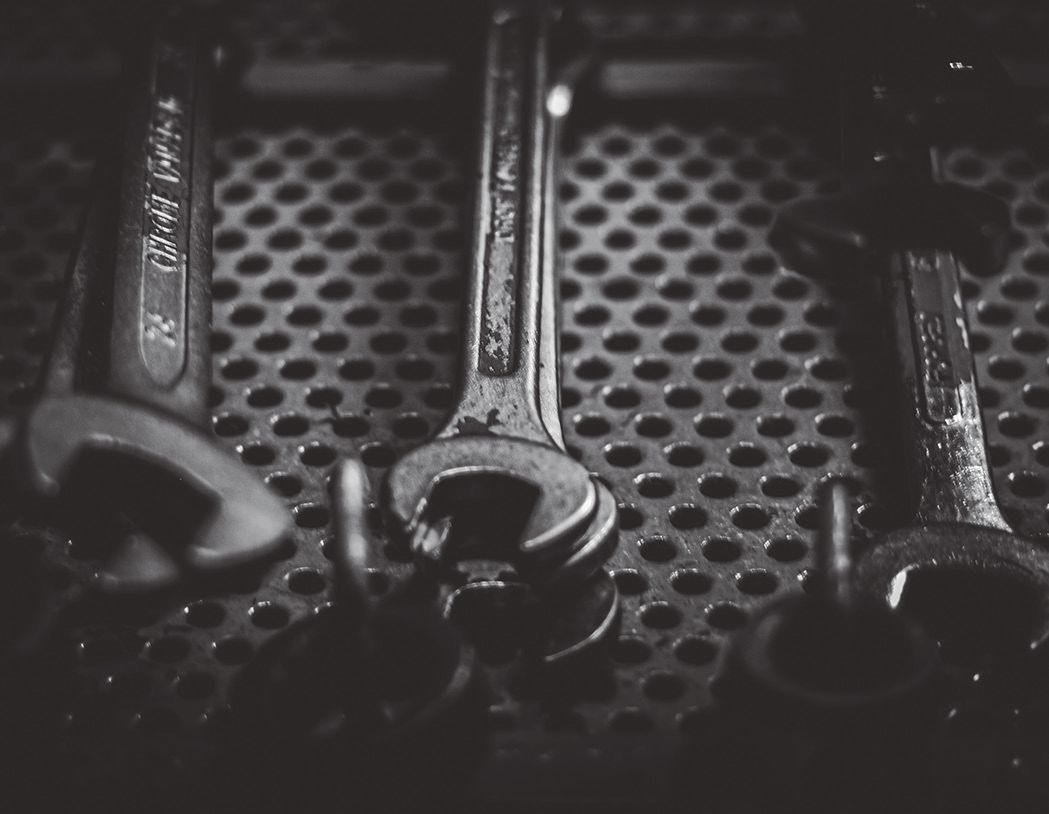 Una fotografía en blanco y negro de tres llaves colocadas sobre una superficie metálica perforada.