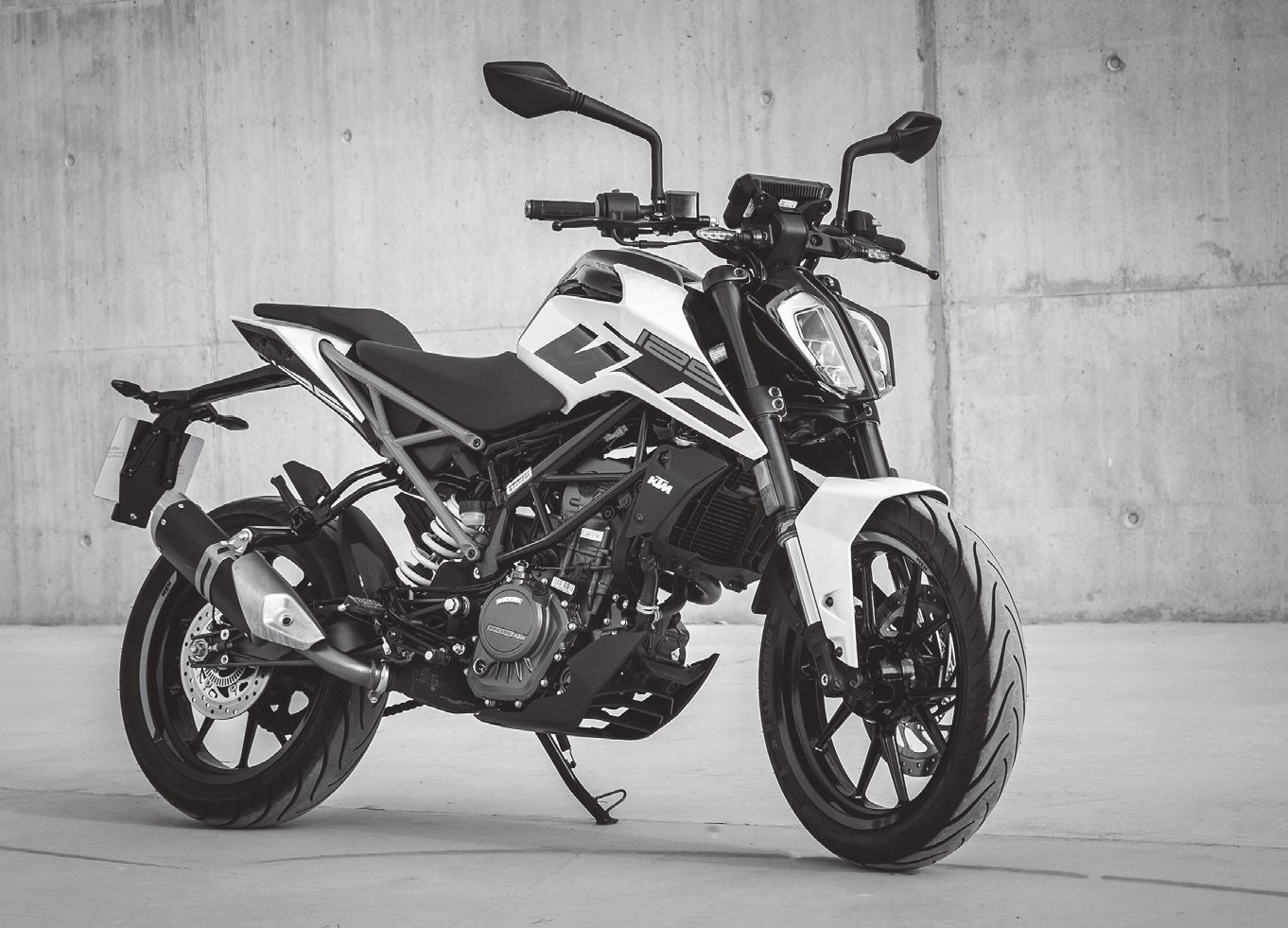 Una fotografía en blanco y negro de una motocicleta estacionada frente a un muro de concreto.