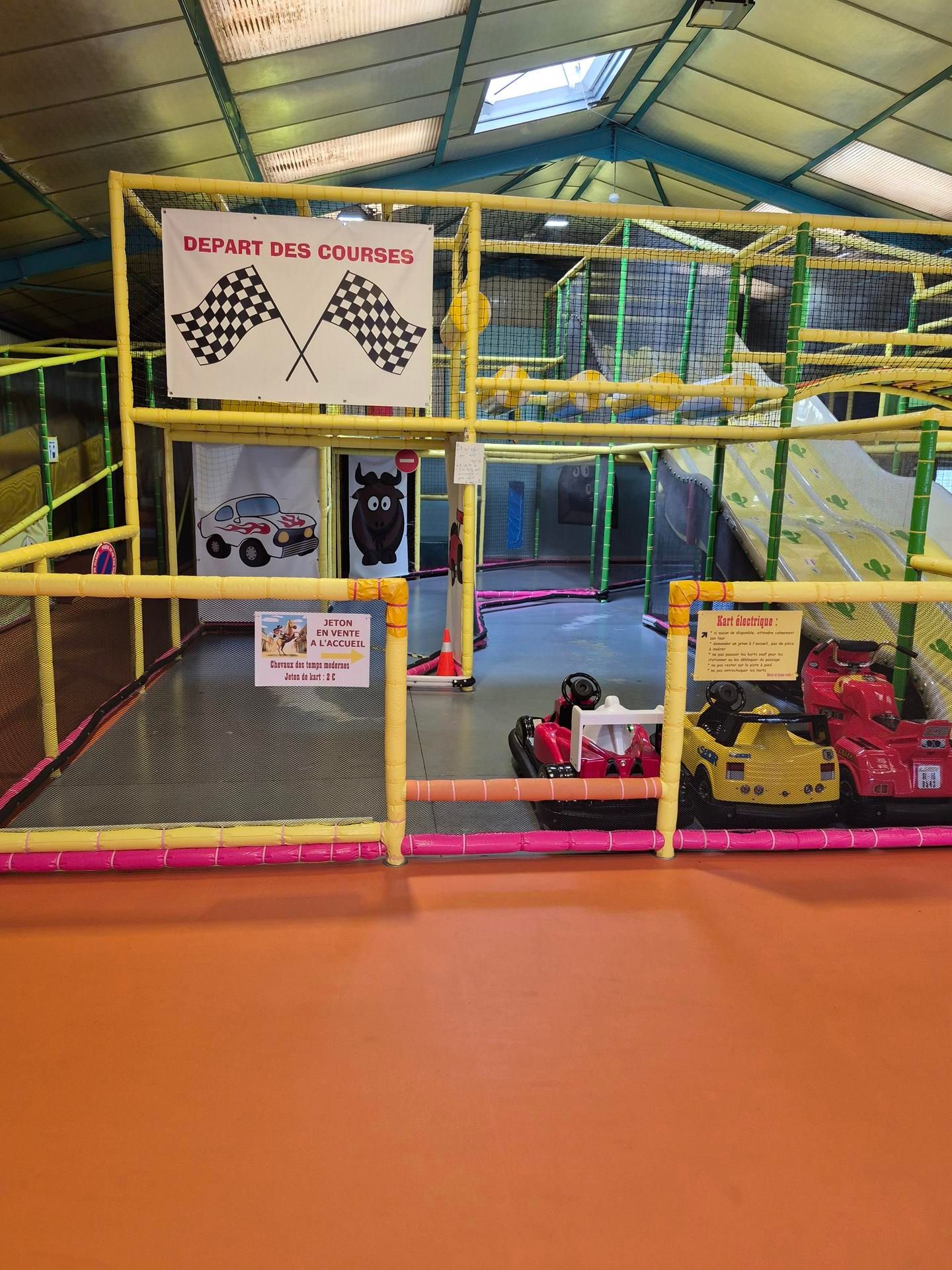 Aire de jeux intérieure avec des petites voitures et un panneau à damier.