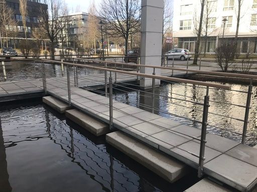 Ein Gehweg mit Handläufen über Wasser in einem städtischen Gebiet.