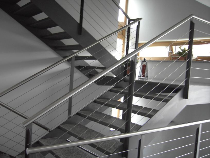 Moderne Treppe mit Stahlhandlauf und Seilgeländer; Innenaufnahme.