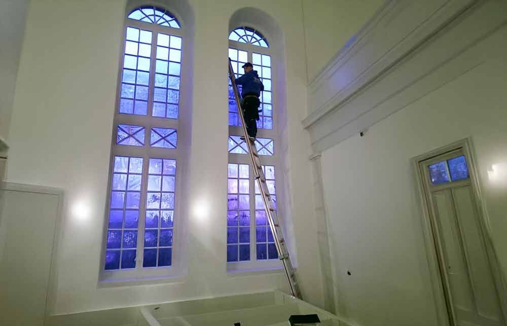 Ein Mann steht auf einer Leiter und putzt ein Fenster.