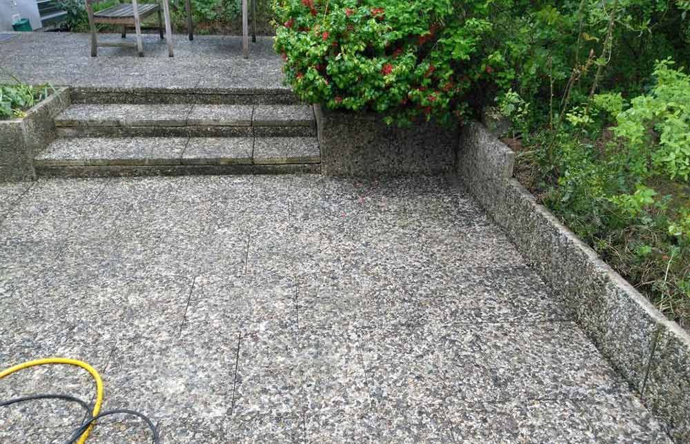 Eine Betonterrasse mit Treppen und einem gelben Schlauch.