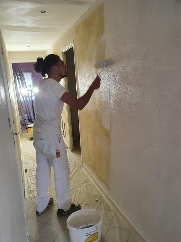 Un artisan avec un rouleau de peinture blanche.