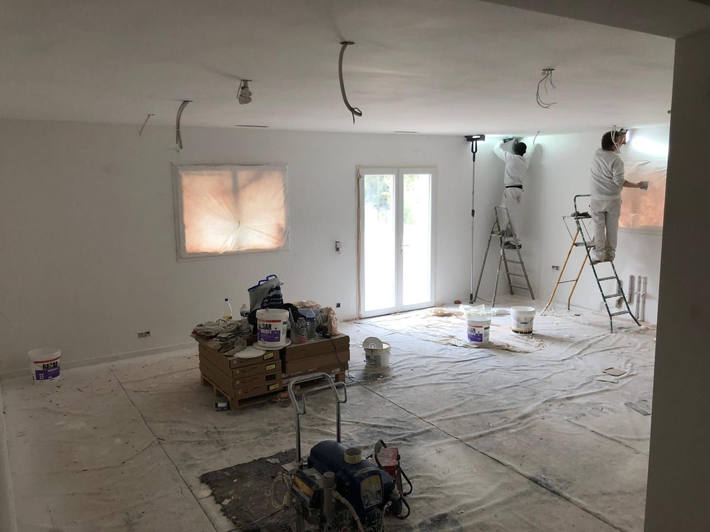 Deux artisans peintres sur des escabeaux.