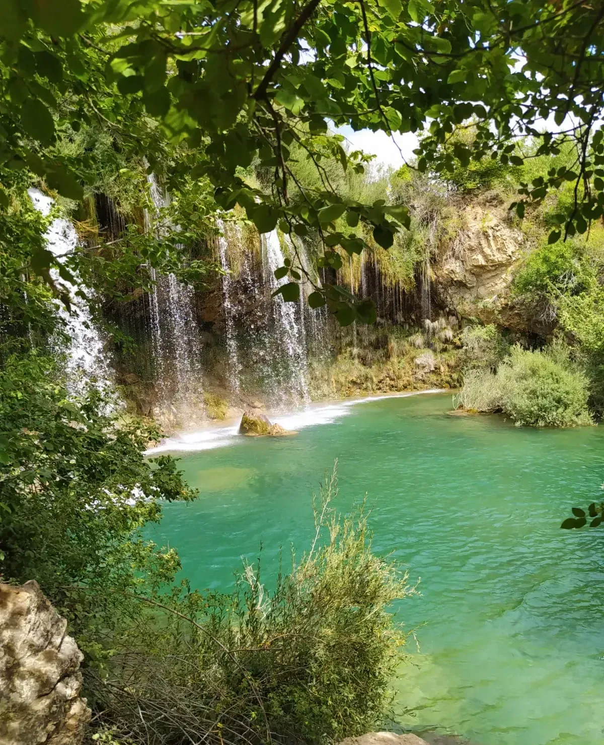 Hay una cascada en medio de un lago rodeado de árboles.