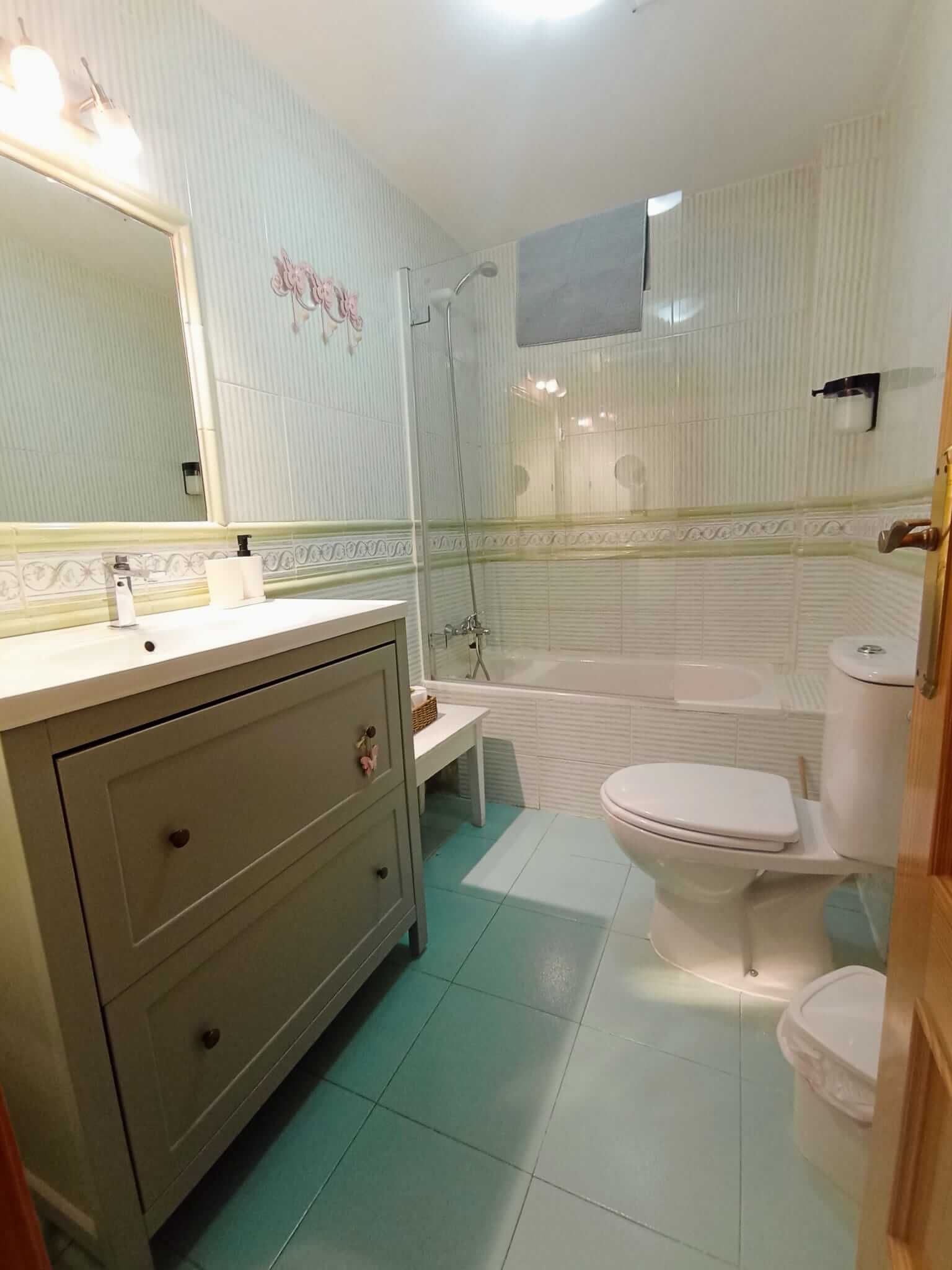 Un baño con inodoro, lavabo, espejo y bañera.