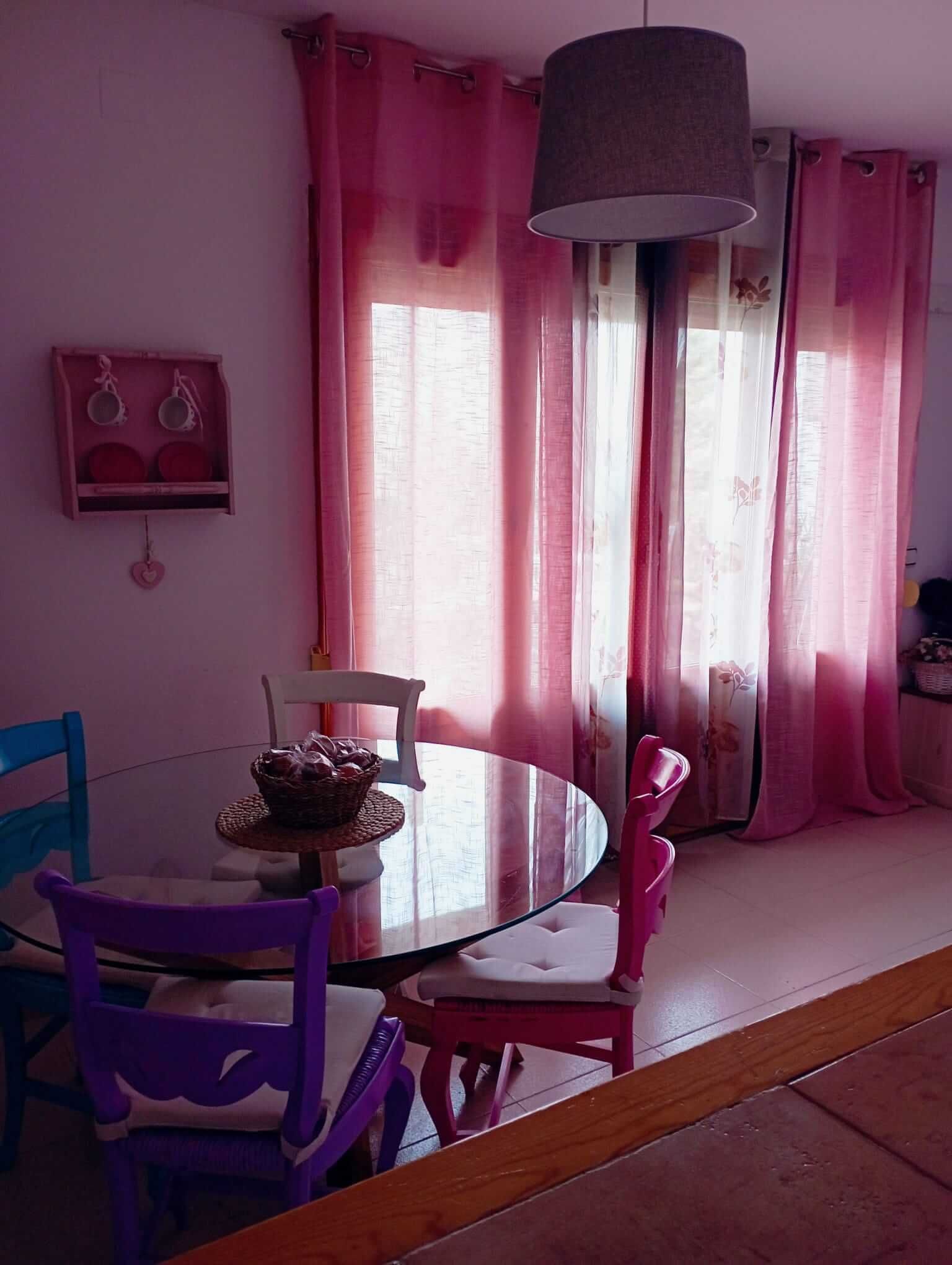 Un comedor con cortinas rosas y una mesa y sillas.